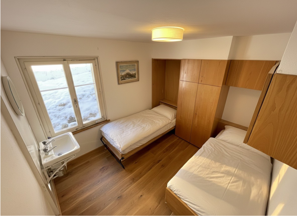 Schlafzimmer mit zwei Einzelbetten, Lavabo und Blick auf die verschneite Landschaft
